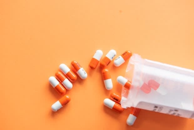 Orange and white pills spilling out of a medication bottle