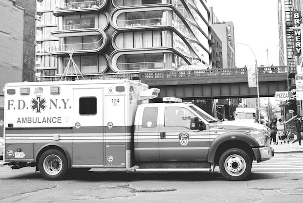 a black and white photo of an ambulance on a busy street