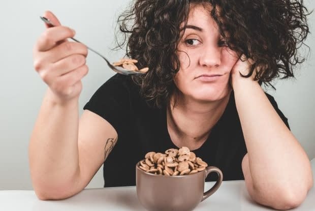 a woman eating cereal from a coffee mug