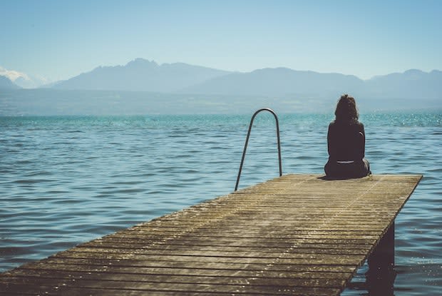 a woman sitting alone on a pier