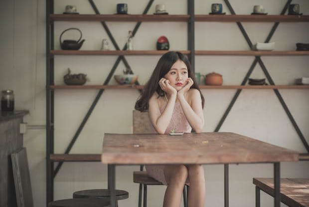 A girl sat at a table looking bored