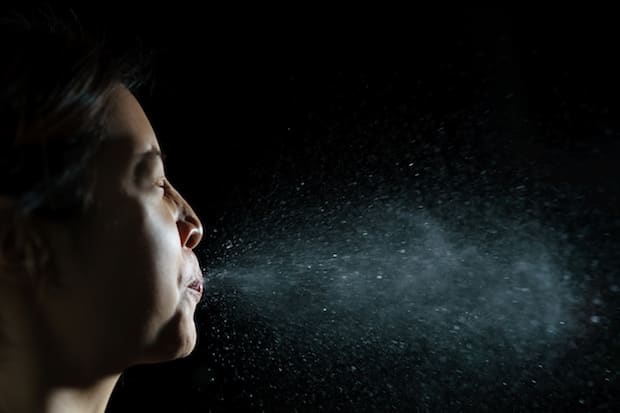 a person sneezing and spraying air droplets