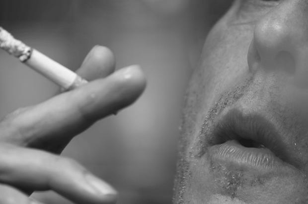 a close up of a man smoking a cigarette