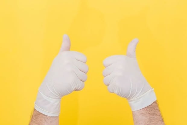 a person wearing gloves giving a thumbs up