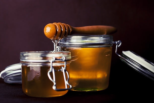 Two jars of honey in front of a black background