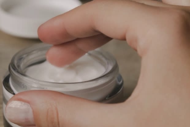 a person dipping their hand into a lotion