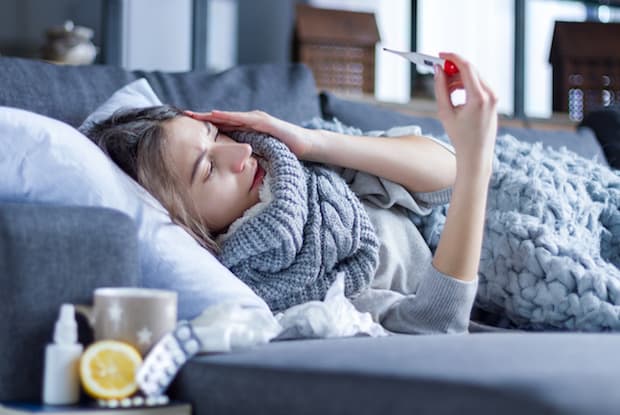 a woman checking her temperature while lying on the couch