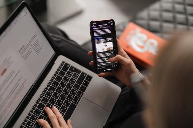 a person on a laptop and phone simultaneously