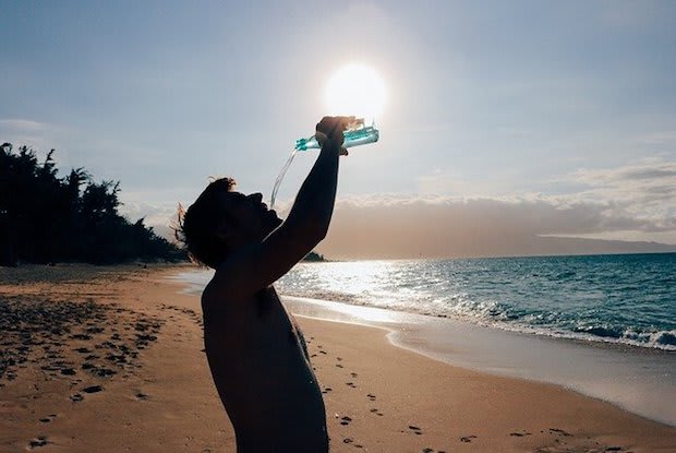 a man drinking water on a beach