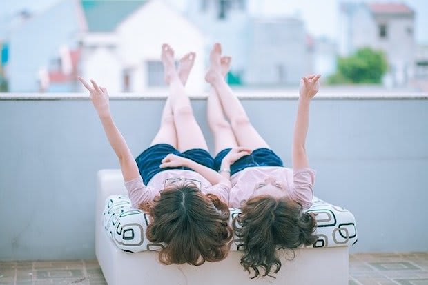 two twin girls sitting on a balcony