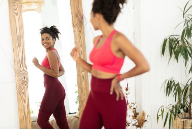 A smiling woman looking in a full-length mirror