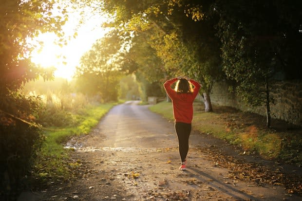 a person walking down a trail with their hands on their head