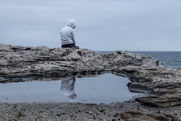 a sad person sitting by the ocean