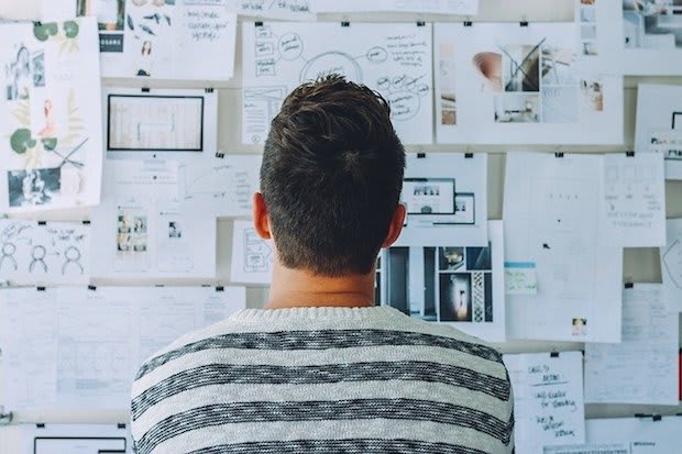 a man looking at papers pinned to a wall