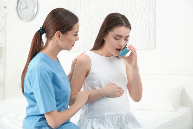 nurse helping pregnant woman with inhaler