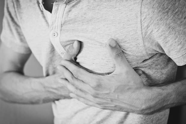 A black and white image of a man clutching his chest in pain