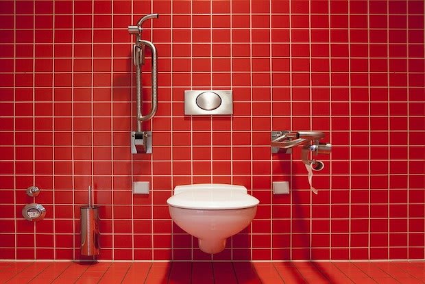 a toilet on a red wall