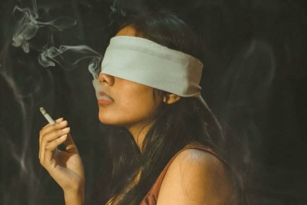 a woman smoking while wearing a blindfold