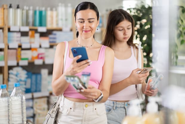 Two women in a pharmacy looking up medications on their phone