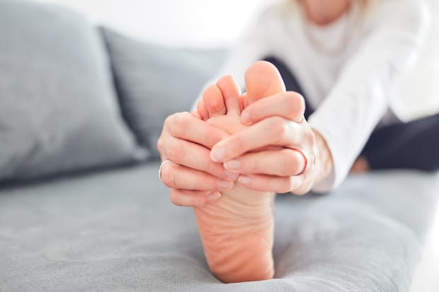 a person massaging her toe to relieve gout pain