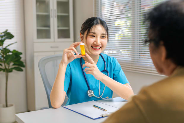 a pharmacist showing their patient the contents of their prescription medication.