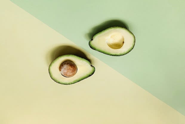 image of avocado cut in half on top of green back drop