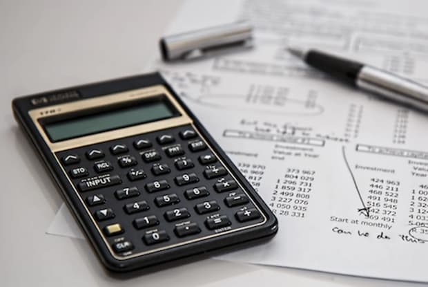 A calculator and a pen on top of a bill