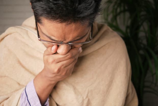 a man sneezing into his hand