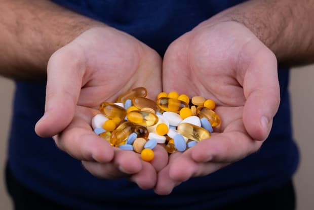 a man holding a handful of different medications