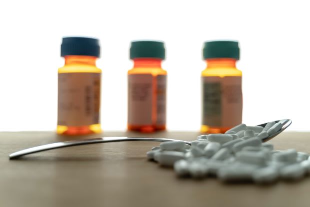 pills on a spoon with pill bottles blurred in the background