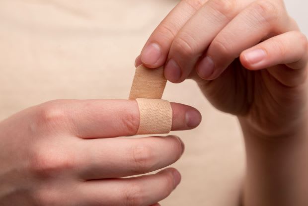 a person applying a band-aid to their finger