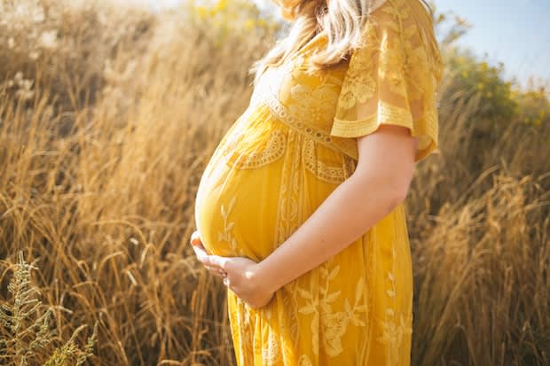 a pregnant woman wearing a yellow dress