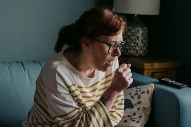 a woman coughing on a sofa