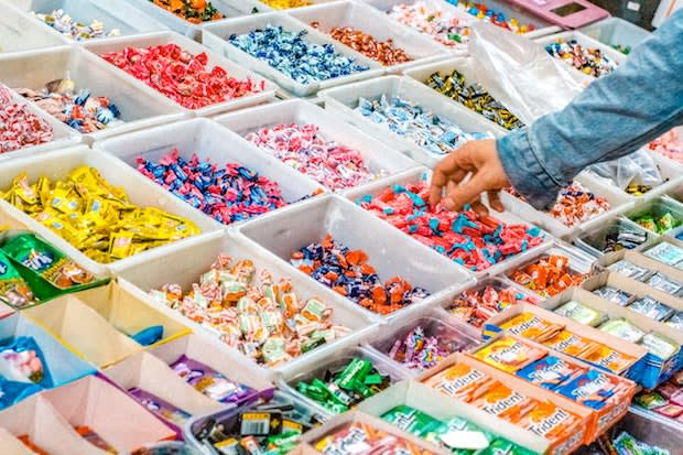 a hand picking out candy at a bulk store