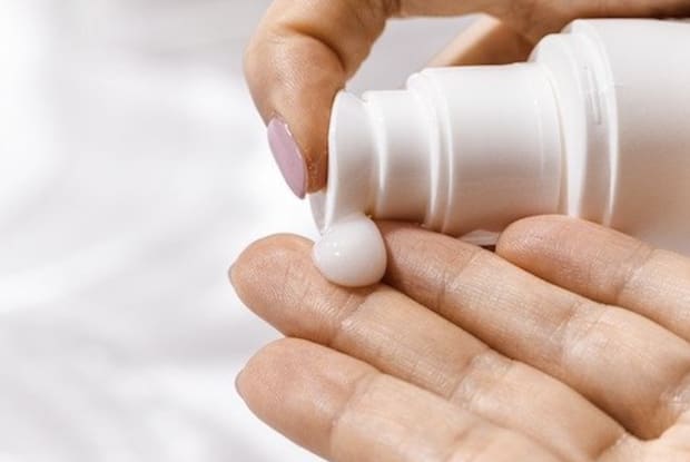 a woman putting lotion on her hands