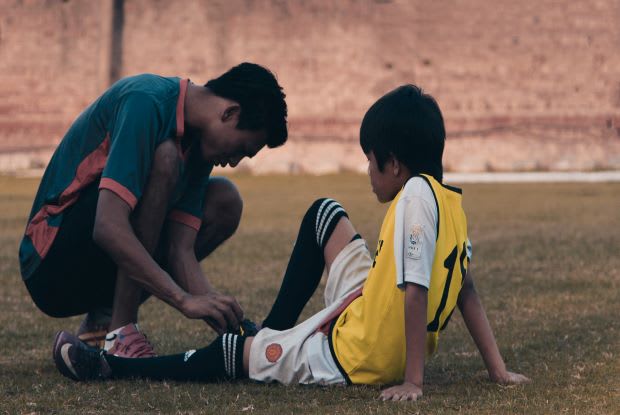 a coach helping a soccer player on the ground