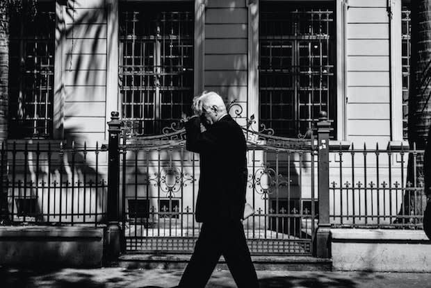 a man holding his head in front of a white building)