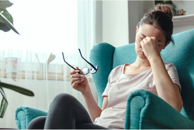 a woman sitting on a sofa feeling unwell