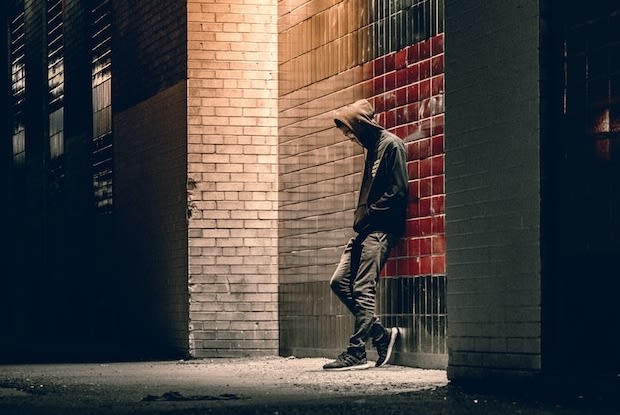 the puddle reflection of a man in a dark alley