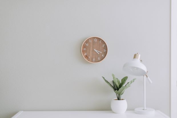 a minimalistic clock hanging over a white desk