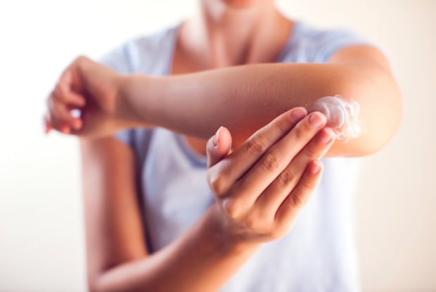 a woman applying cream to her elbow