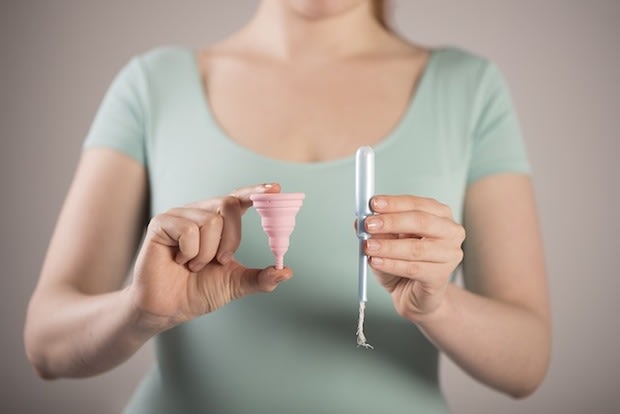 a woman holding a tampon and a menstrual cup