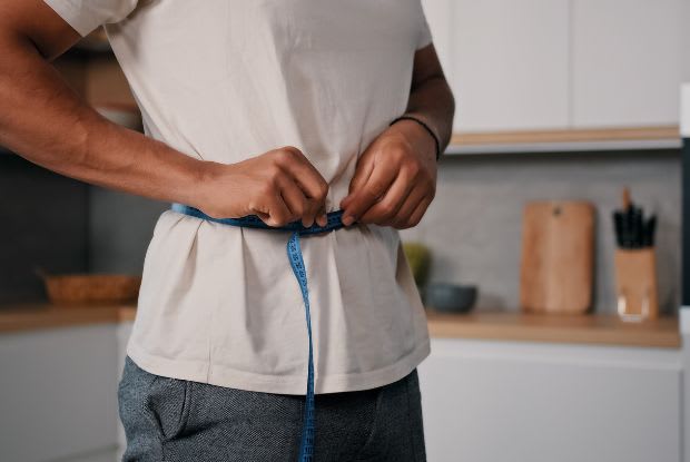 A man measuring his waist with a measuring tape