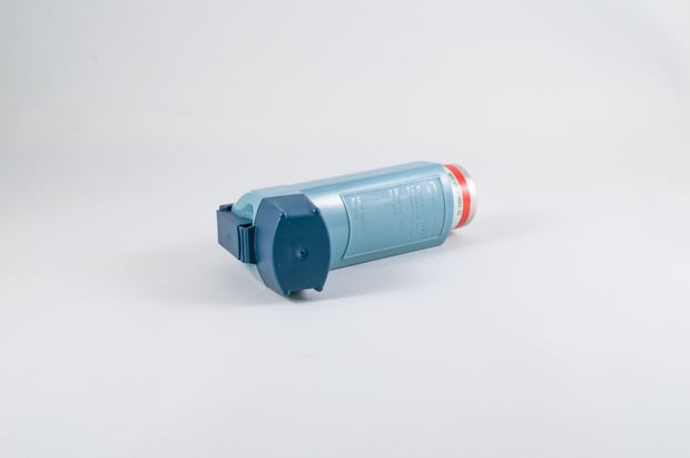 An asthma inhaler in front of a blank background