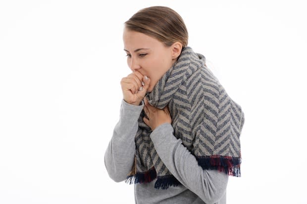 A woman coughing into her hand