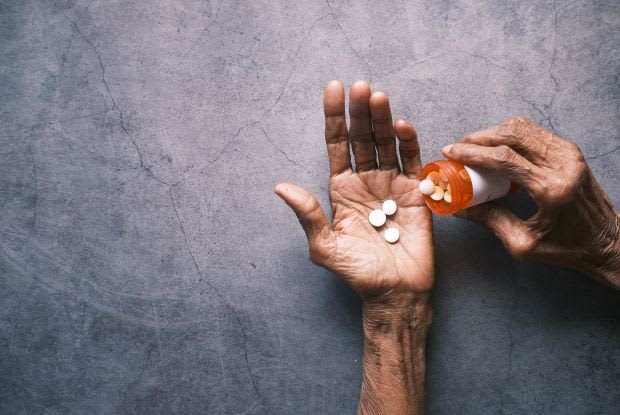 a person putting pills into their palm