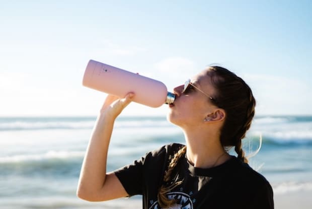 a woman drinking out of a water bottle