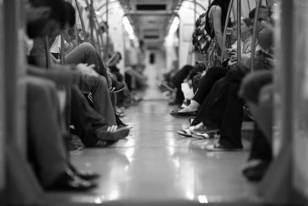 A black and white image of people sitting on the subway