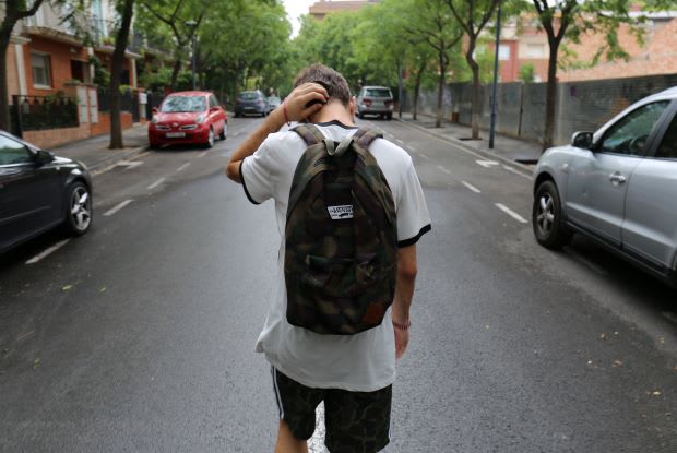 a teenager wearing a backpack walking down the street