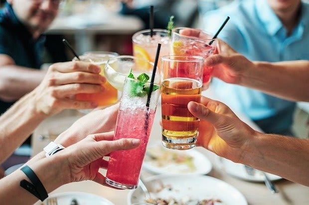 several people clinking alcoholic drinks together